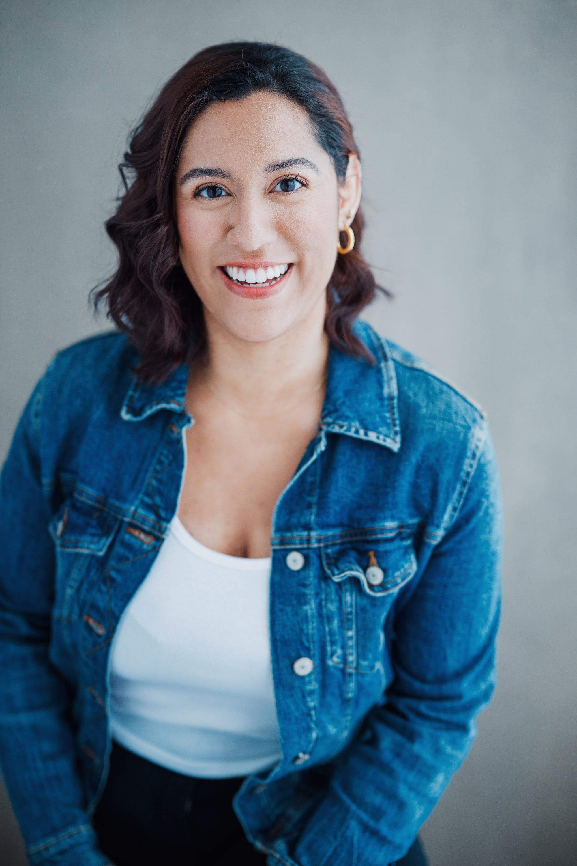 Portrait of Kaide Solano smiling, wearing a denim jacket over a white top