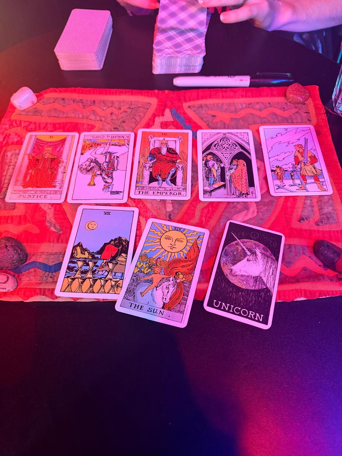 Tarot cards, including The Sun and The Emperor, laid out on a red cloth